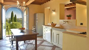 A kitchen with a dining table, a refrigerator, and a view of the outdoors. - Villa Scuderie -  Guardistallo, Pisa (Guardistallo)