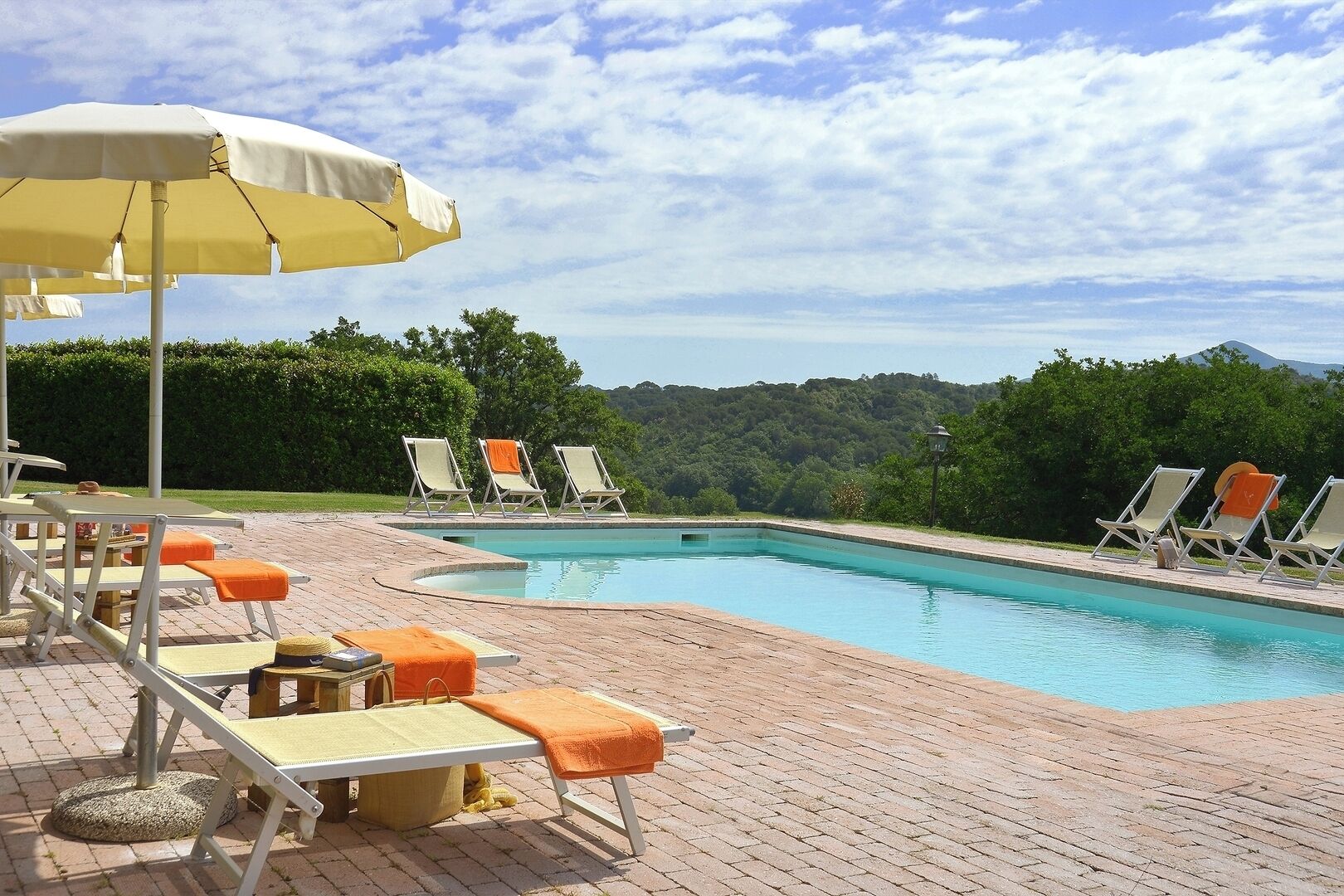 A poolside area with lounge chairs, a table, and an umbrella.