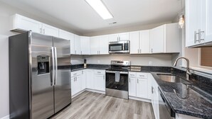 A modern kitchen with white cabinets, stainless steel appliances, a granite countertop, and a built-in oven. - Stay @ Rapp on the Rappahannock River, Welcome & Relax! (Dunnsville)