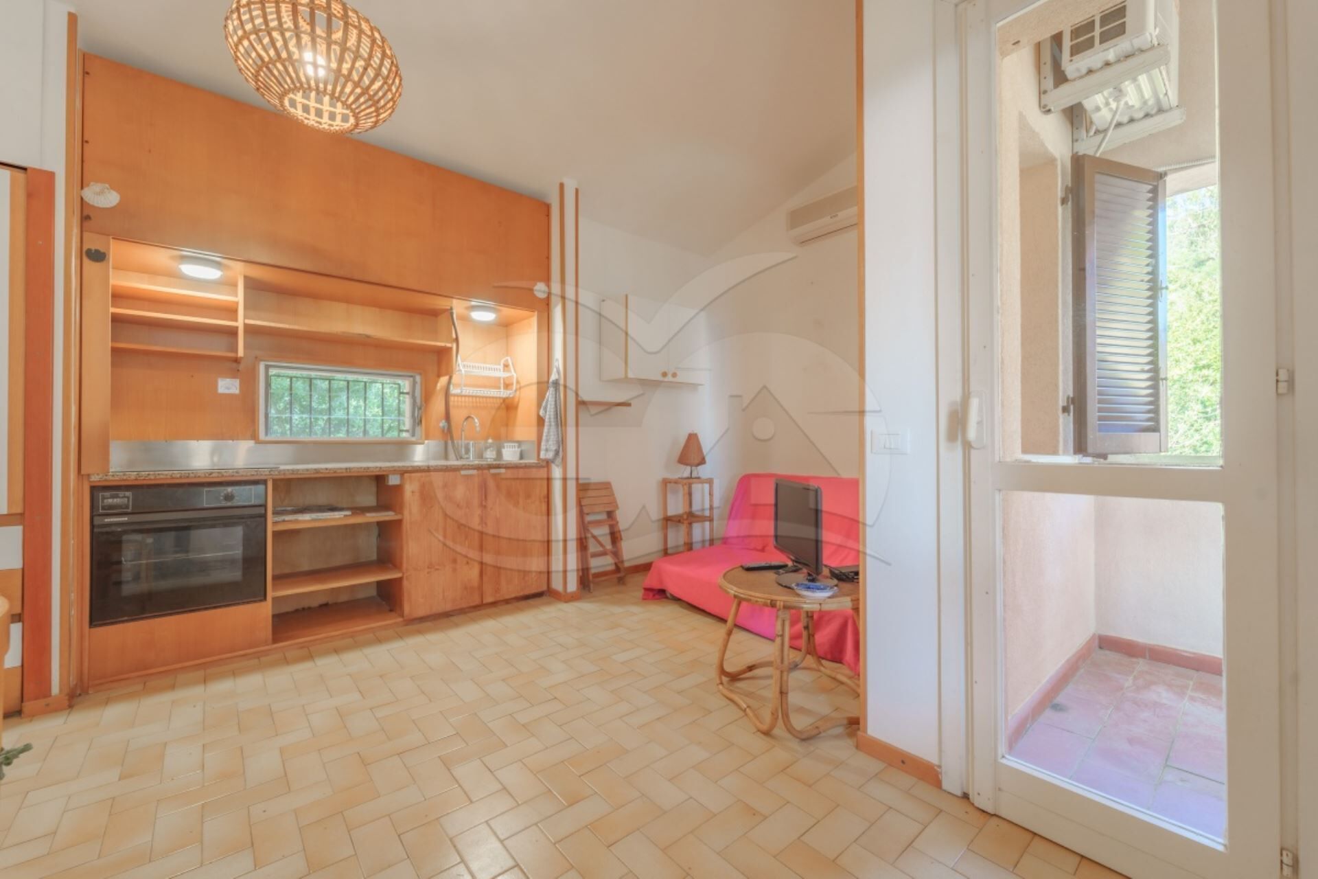 Eine kompakte Küche mit Holzausstattung, einem eingebauten Backofen und einem Fenster.