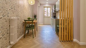A narrow hallway with a dining table and chairs, a radiator, and a hanging light fixture. - Amelie   Jewel of Trastevere (ROMA)