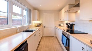 Una cocina moderna con armarios blancos, una estufa negra y una ventana que proporciona luz natural.