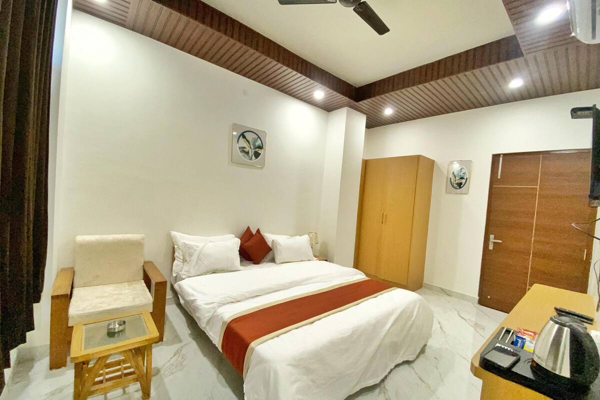 A hotel room with a bed, a chair, a small table, a wardrobe, and a ceiling fan.