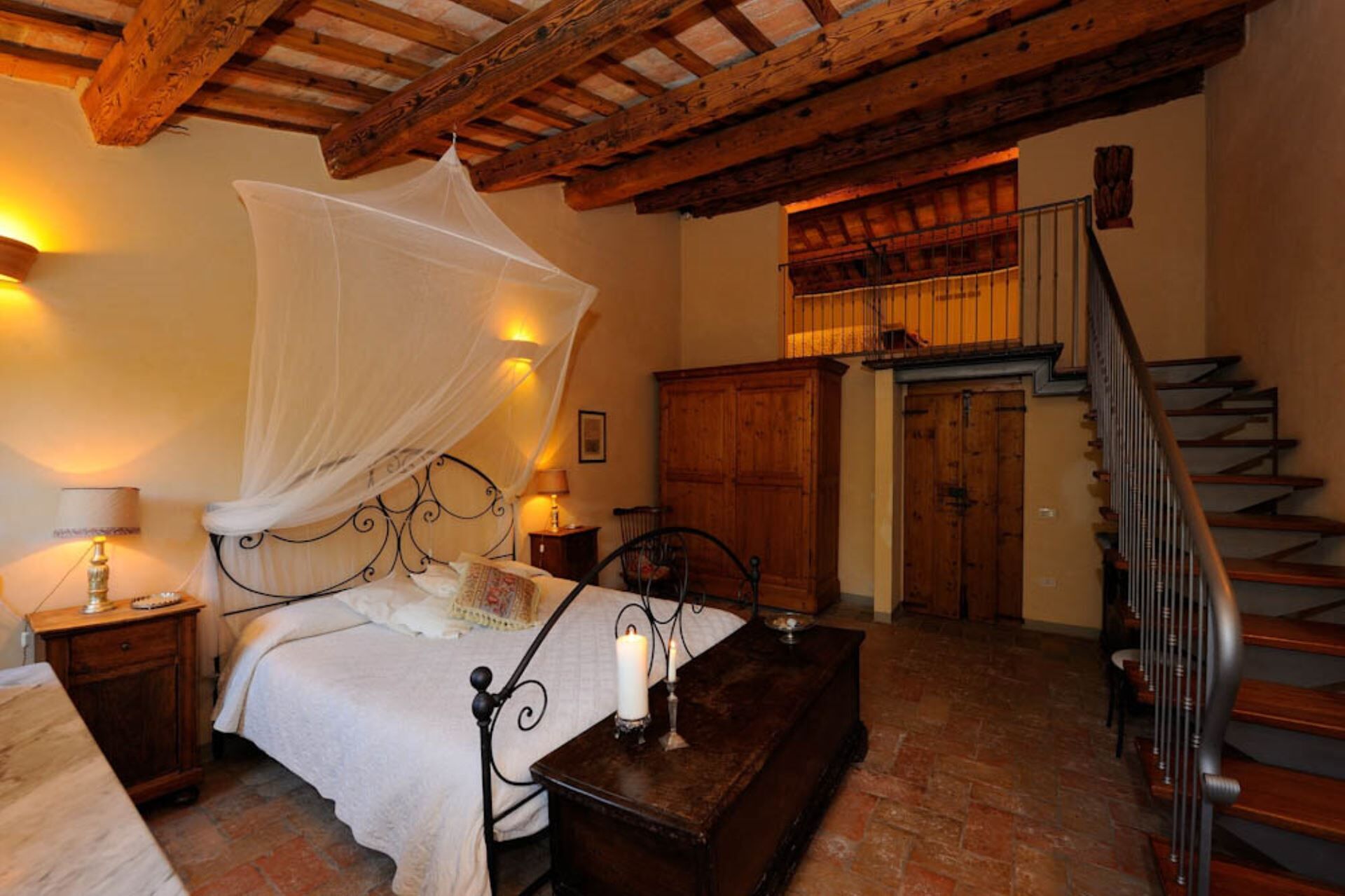 Quarto com cama sob dossel, escada de madeira e armário de madeira.