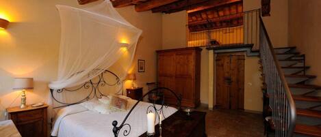 Quarto com cama sob dossel, escada de madeira e armário de madeira.
