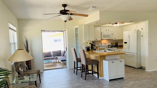 A modern kitchen with white cabinets, a central island, and a ceiling fan. - Close to Best Gulf Beaches, Downtown Venice & Wellen Park - Long Term Available (Venice)