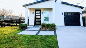 Et moderne hus med to etager, en garageport i sort farve, en fordør med glasindlæg og en lille forhave med en sti til indgangen.