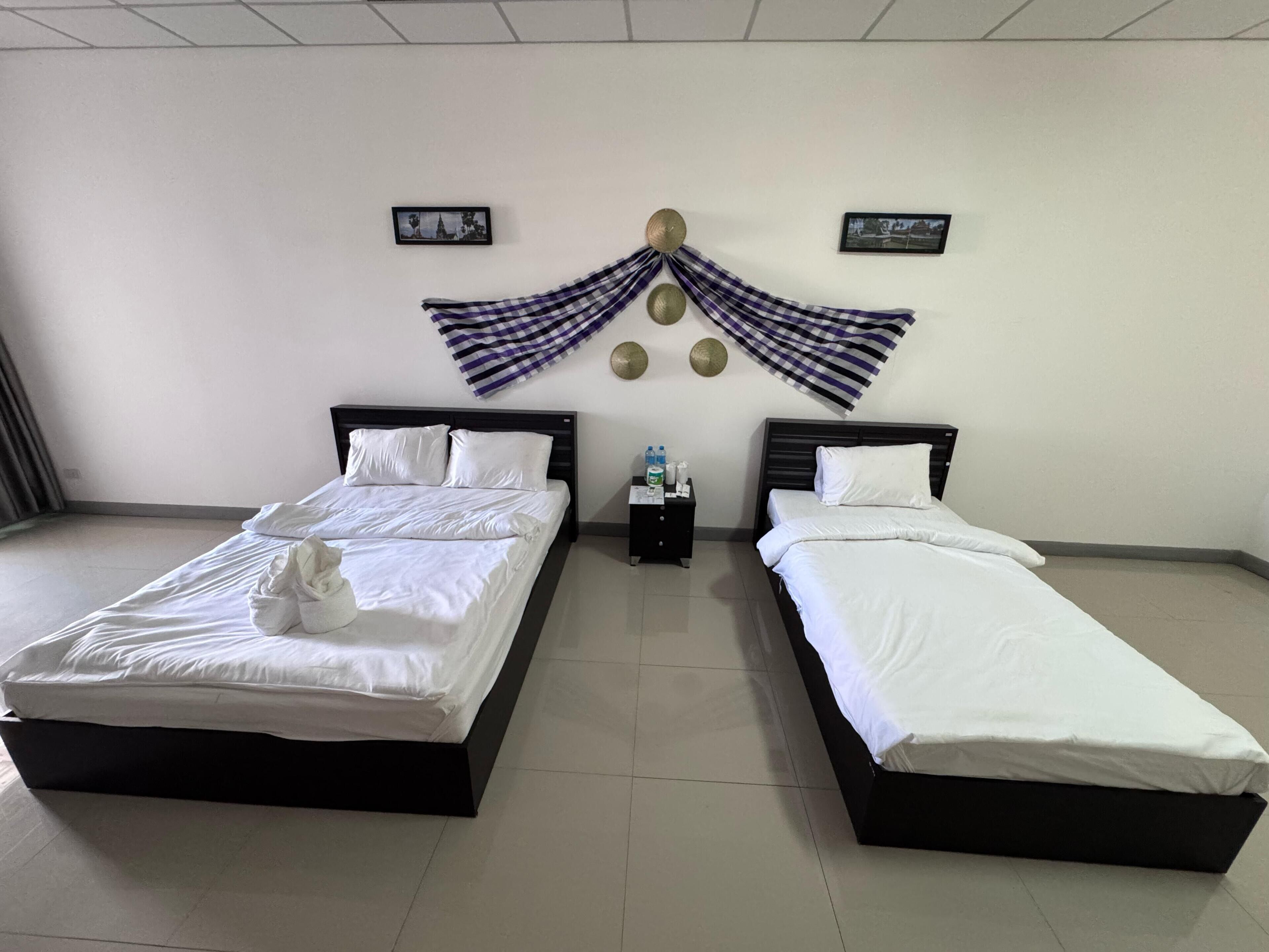 Una habitación de hotel con dos camas, una mesita de noche y adornos en la pared.