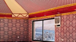 A dining area with wooden furniture and patterned walls. - Siwar Luxury Camp  (Wadi Rum)