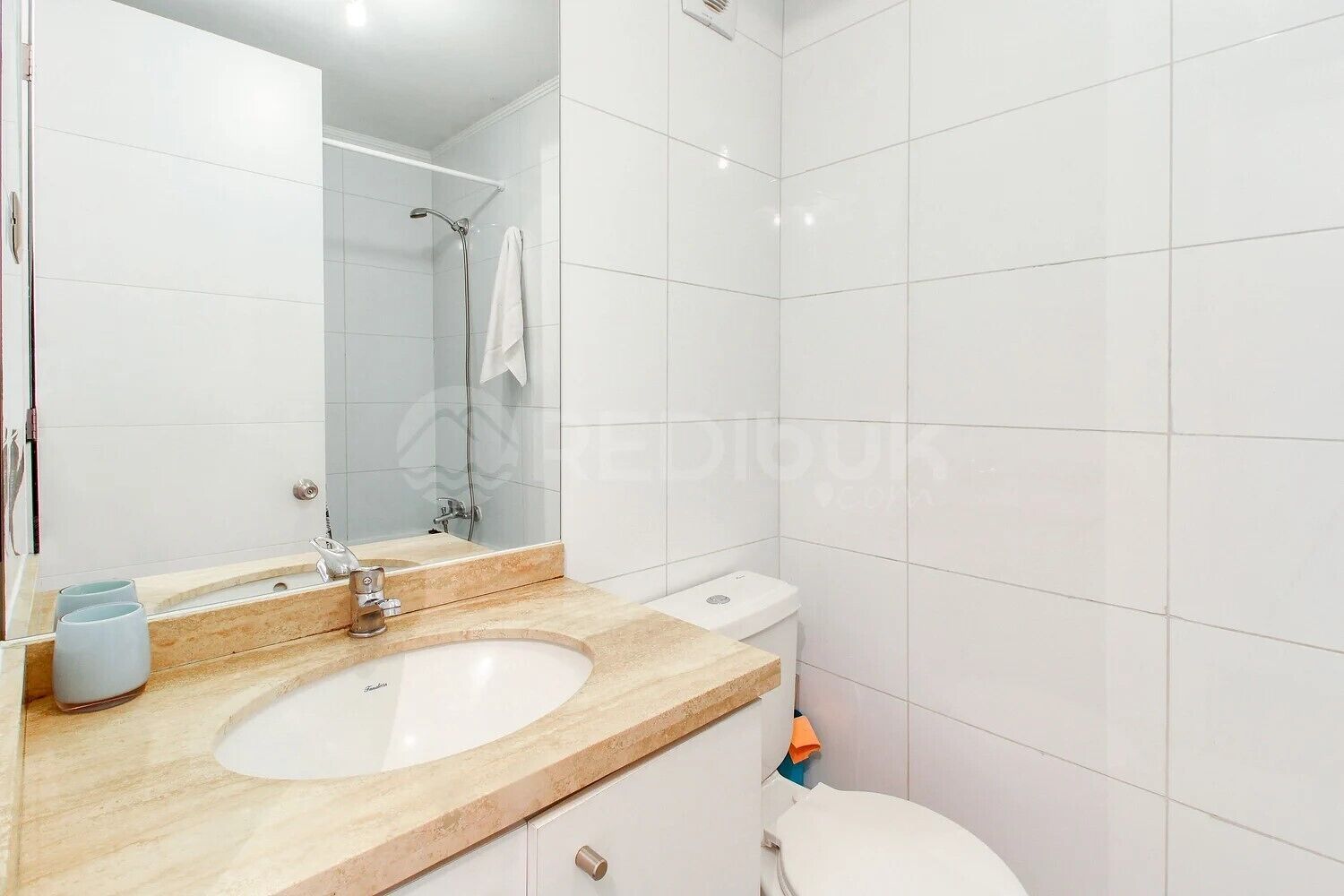 A modern bathroom with a large mirror, a sink, and a toilet.