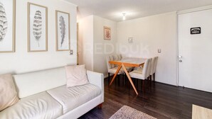 Uma sala de estar com sofá, uma mesa de jantar com cadeiras e obras de arte emolduradas na parede.