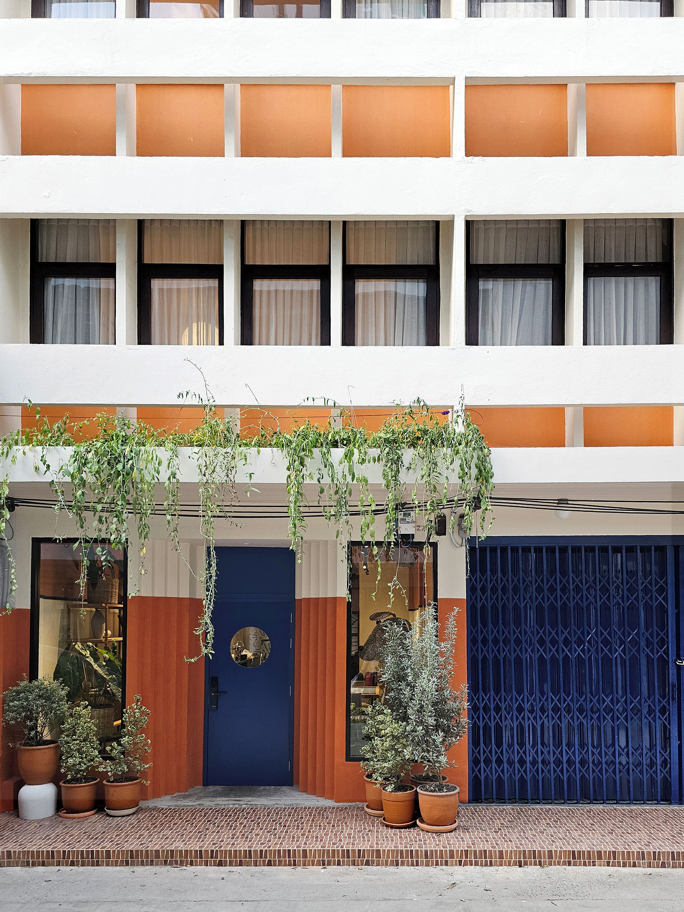 Ein Hotel mit einer blauen Tür, Blumentöpfen und einer blauen Garagentür.