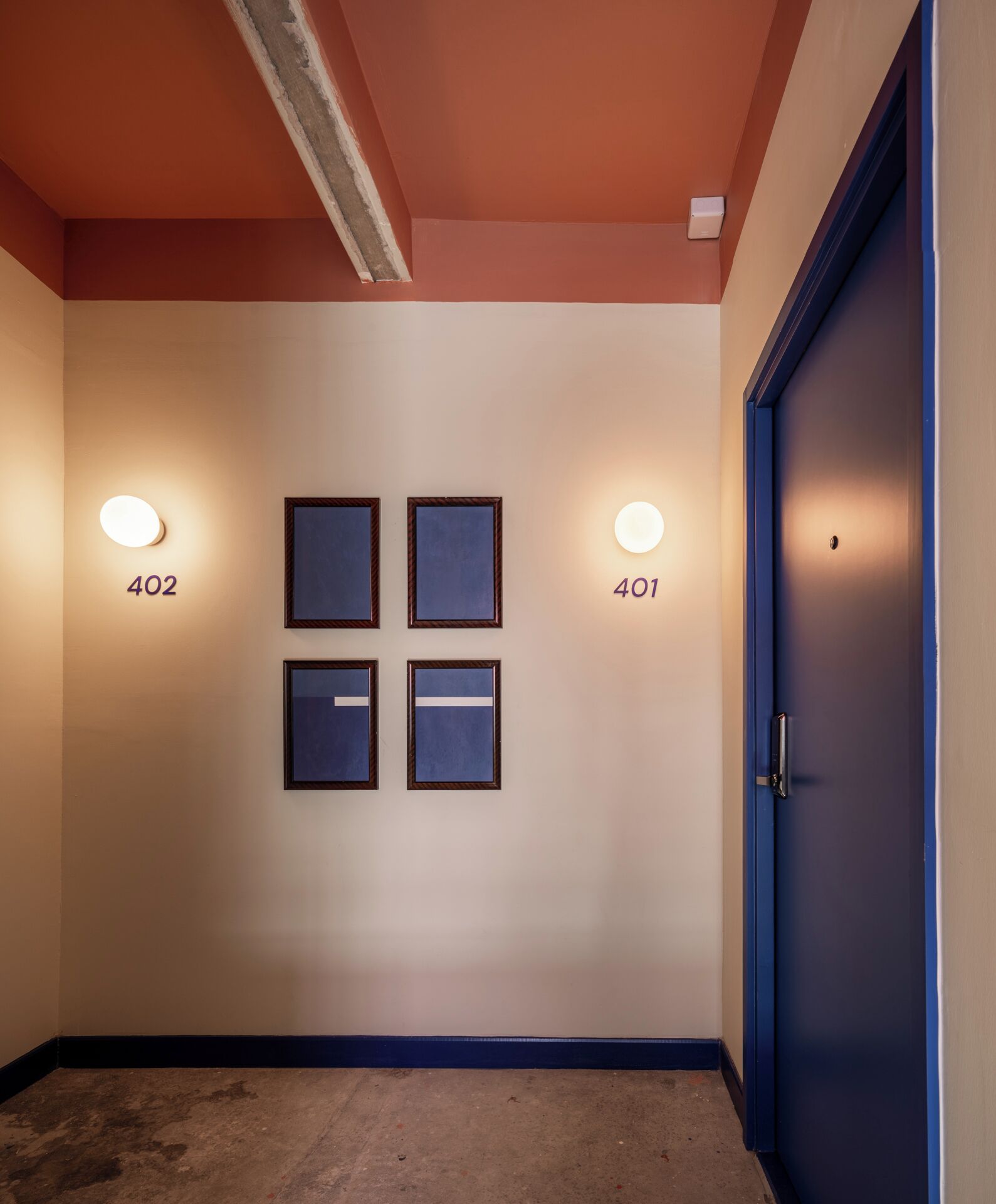 A hallway with four framed pictures on the wall, two doors labeled 402 and 401, and a blue door on the right.
