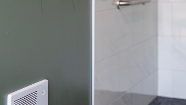 Une salle de bain avec deux crochets pour serviettes au mur et un porte-serviettes au sol.