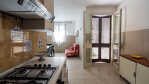 A kitchen with a gas stove, a sink, and a red chair. - Villino Sole 1 Airco Near Beach & Centre (Porto Cesareo)