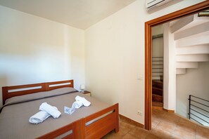 A bedroom with a wooden bed, a nightstand, and a staircase leading to an upper floor.