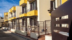 Una hilera de edificios amarillos con balcones y una entrada protegida por una reja.