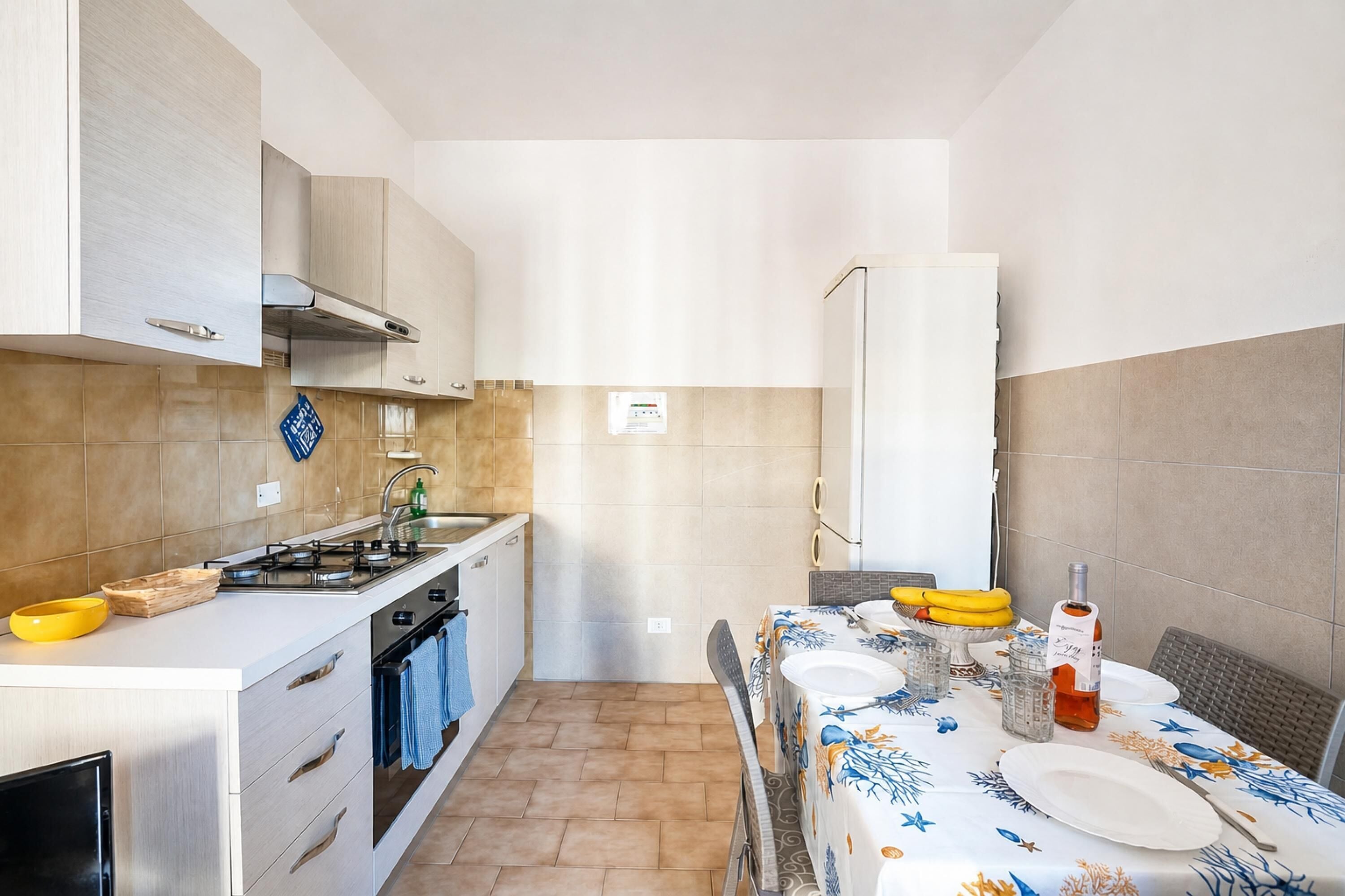 Una cocina compacta con estufa, horno y gabinetes blancos.