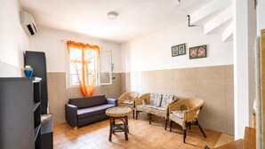 A modern living room with a sofa, two wicker chairs, a small round table, and a television. - Villino Sole 3 With A/C Near Beach & Centre (Porto Cesareo)