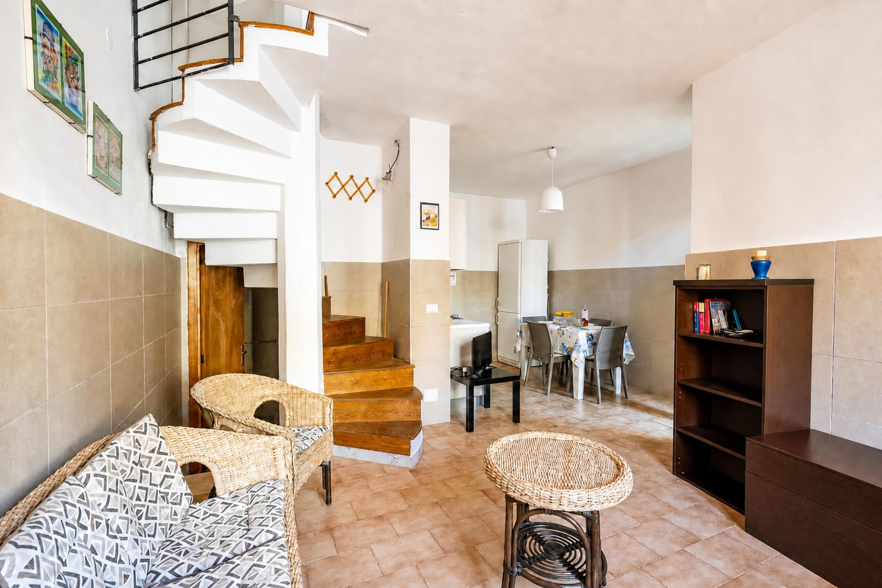 Un interior moderno con una escalera, un comedor y una estantería.