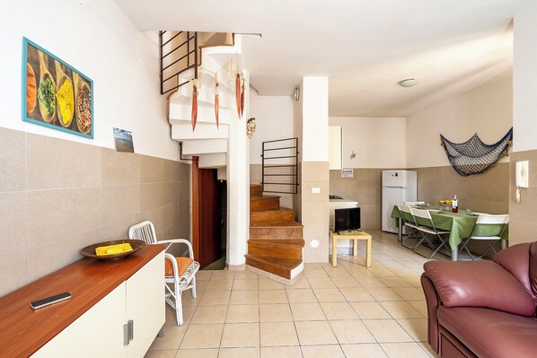 A compact living space with a kitchen, dining area, and a staircase leading to an upper level. - Villino Sole 4 Airco Near Beach & Centre (Porto Cesareo)