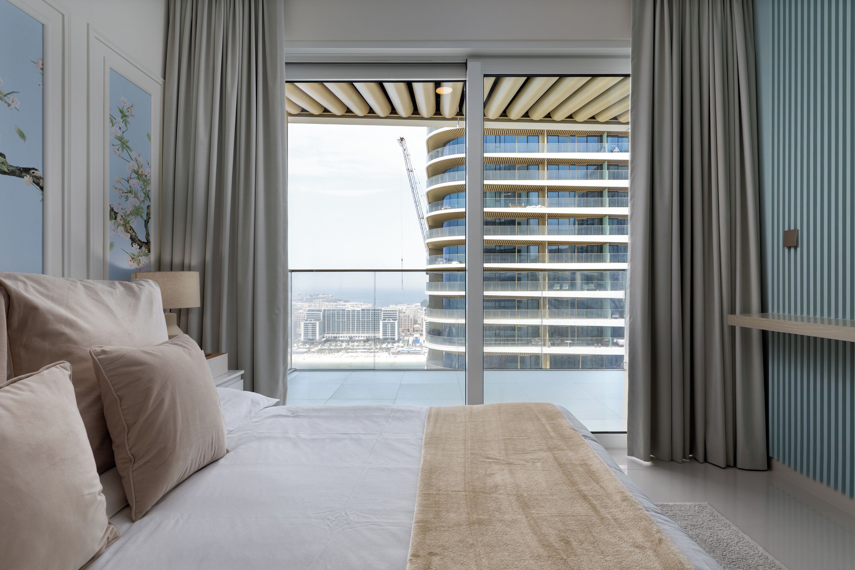 Une chambre d’hôtel moderne avec un grand lit, une vue sur un immeuble de grande hauteur et un balcon donnant sur le panorama de la ville.