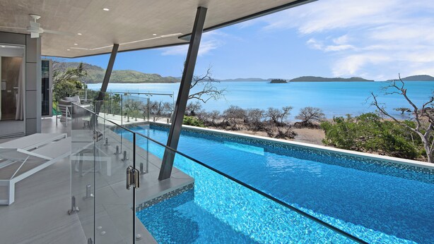 Ein moderner, überdachter Pool mit Glasgeländern, Meerblick und minimalistischem Design.