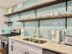 A kitchen with a gas stove, microwave, sink, and a coffee maker.