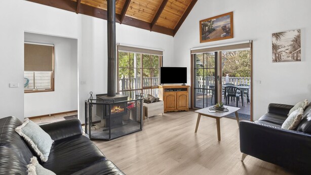 Un salon spacieux avec un haut plafond, une cheminée, un téléviseur et un balcon doté de meubles d’extérieur.