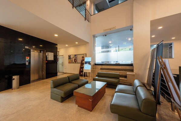 A lobby with a reception desk, seating area, and a view of the swimming pool. - THE Woodrose (Bengaluru)