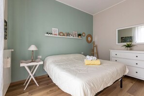Une chambre à coucher comprenant un lit, une table de chevet, une commode, un miroir et des éléments décoratifs sur les murs.
