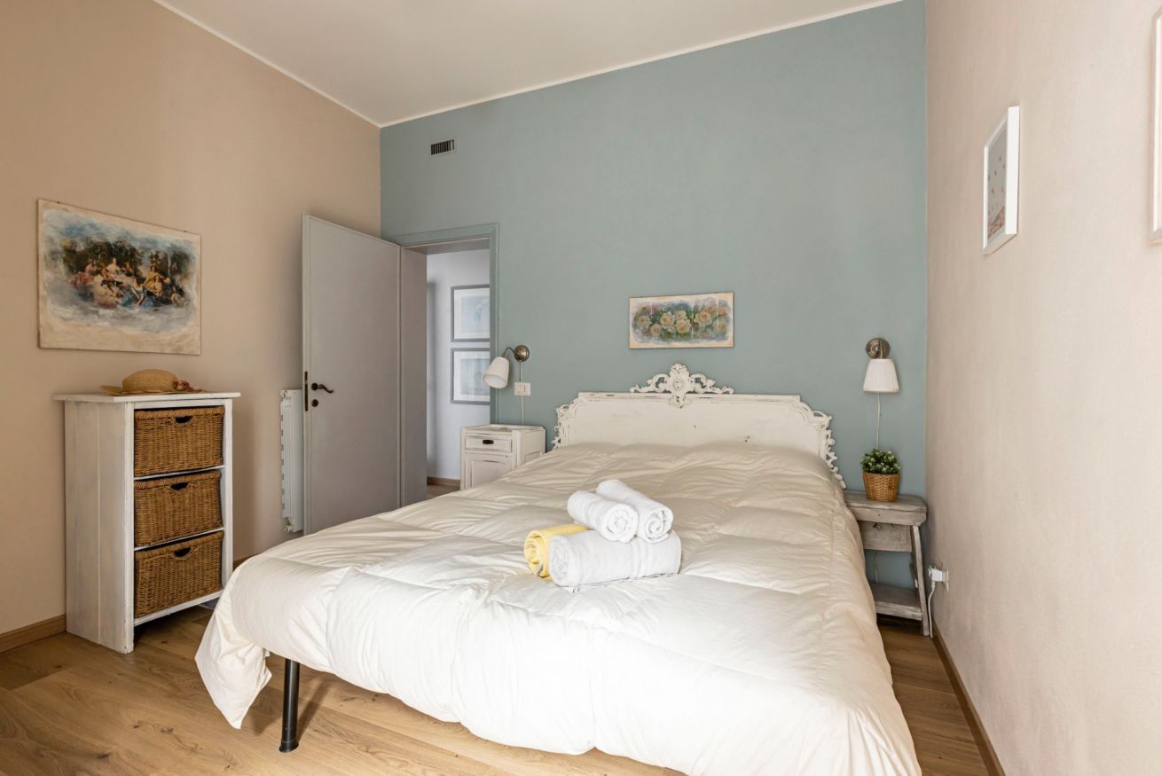 A bedroom with a bed, a dresser, a nightstand, and a door leading to another room.