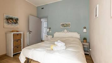 A bedroom with a bed, a dresser, a nightstand, and a door leading to another room.
