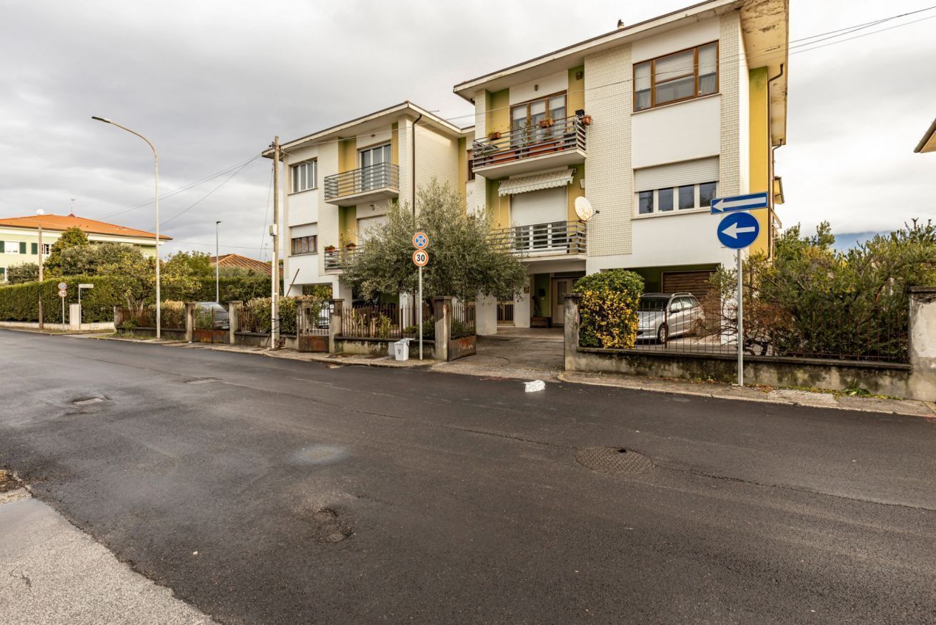Una calle residencial con casas de dos pisos, una señal de límite de velocidad y una señal de dirección.
