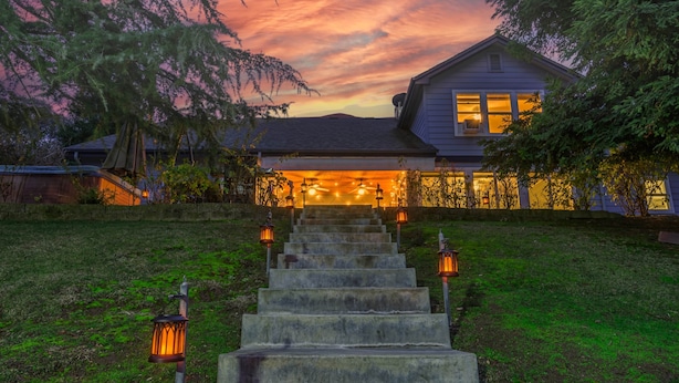 A house with a front porch, a staircase leading to the entrance, and a sunset sky. - Blue Resort of Yosemite-Pool, Hot Tub, Theatre and Games (Mariposa)