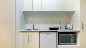 A compact kitchenette with a sink, a coffee maker, a toaster, and a microwave.