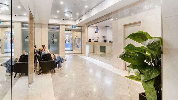 Un lobby moderno con una recepción, un área de descanso y una planta grande.