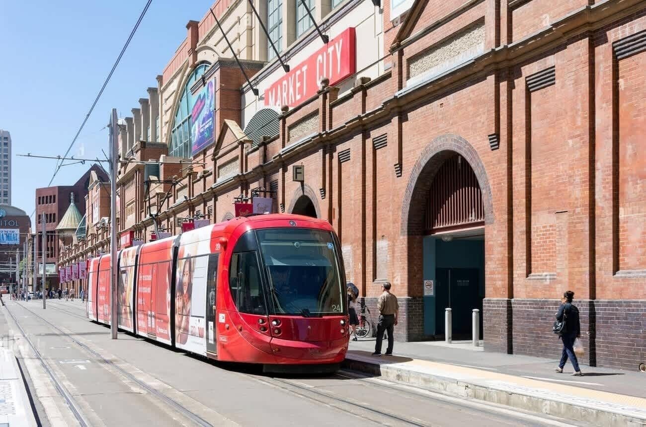 A red tram on a city street with a Market City sign above.
