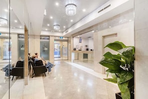 Un vestíbulo moderno con una recepción, zona de estar y una planta grande en maceta.
