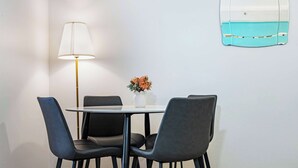 Un coin repas comprenant une table ronde, quatre chaises, une lampe et un vase avec des fleurs.