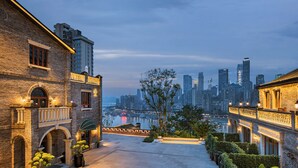 A courtyard with a view of a city skyline, featuring a mix of traditional and modern architecture. - CHONGQING MANQUE MANSION (Chongqing)
