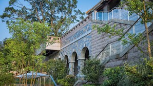 A stone building with a staircase, glass railing, and greenery. - CHONGQING MANQUE MANSION (Chongqing)