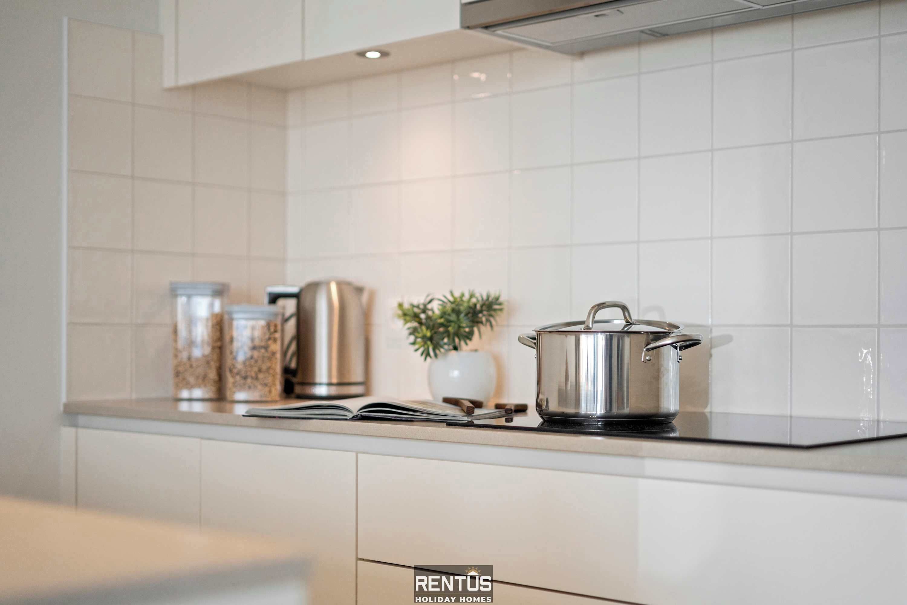 Une cuisine moderne avec des meubles blancs, un plan de travail noir et des appareils électroménagers en acier inoxydable.