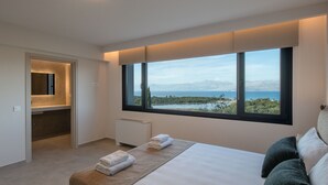 Une chambre à coucher moderne avec une grande fenêtre, un lit, une table de chevet et une armoire intégrée.