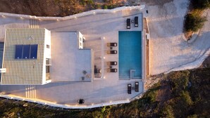 Vue aérienne d’un complexe hôtelier doté d’une piscine, de chaises longues et d’une terrasse couverte.