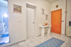 A hallway with a white door, a wooden door, and a small table with a vase and a bowl.