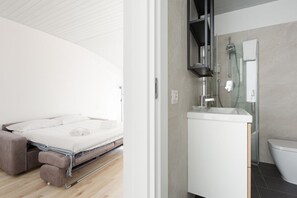 A modern bedroom with a bed, a sofa, and a bathroom with a sink and toilet. - GuestHost - Milan- Corso Lodi Studio with AC & WIFI (Milano)