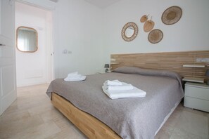A bedroom with a bed, a bedside table, a nightstand, a mirror, and wall decorations.