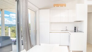 Une cuisine moderne avec des meubles blancs et un coin repas doté d’une table.