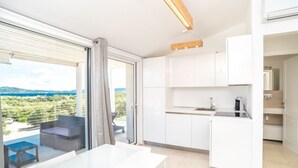 Une cuisine moderne avec des armoires blanches, un four encastré et une vue sur un balcon agrémenté d’une table et de chaises.
